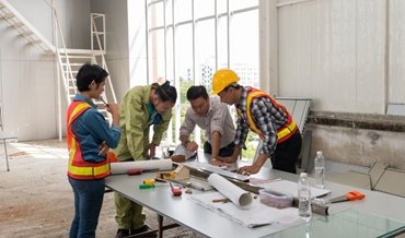 a group of engineers looking at building plans on a table
